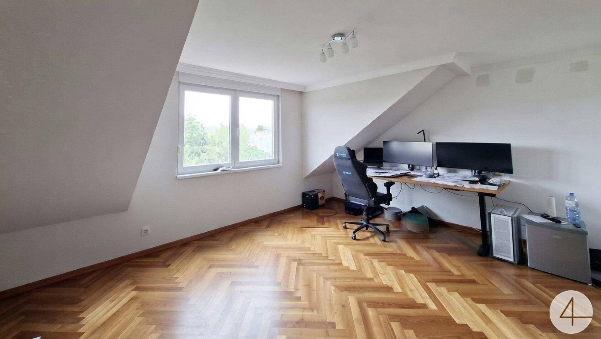 Dachgeschosszimmer als Büro genutzt mit Fischgrätparkett und schrägen Wänden.