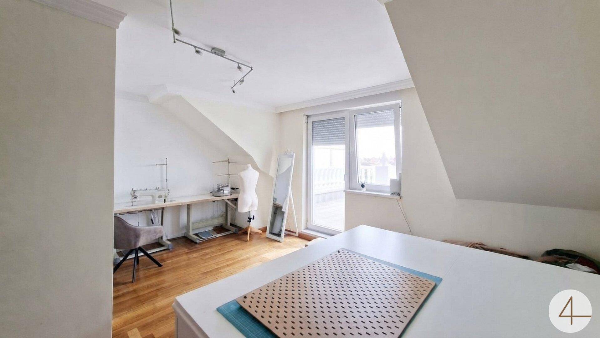 Dachgeschosszimmer mit Fischgrätparkett und Zugang zu einem Außenbereich.