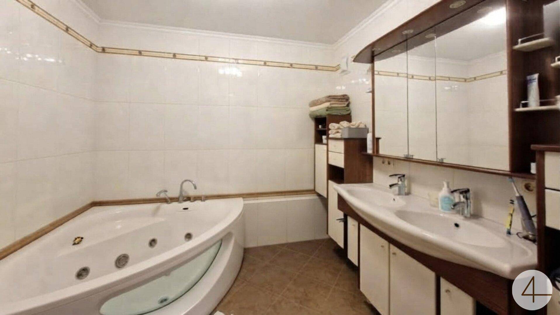 Geräumiges Badezimmer mit Eckbadewanne, Doppelwaschbecken und Spiegelschrank.