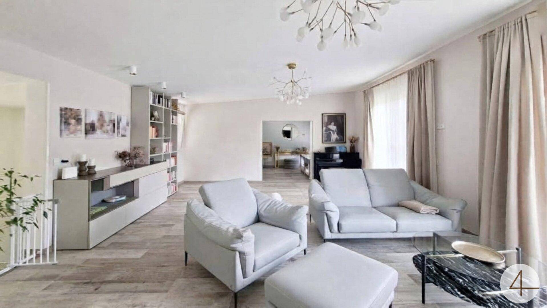 Elegantes Wohnzimmer mit bequemen Sofas, modernem Bodenbelag und Blick auf einen Arbeitsbereich.