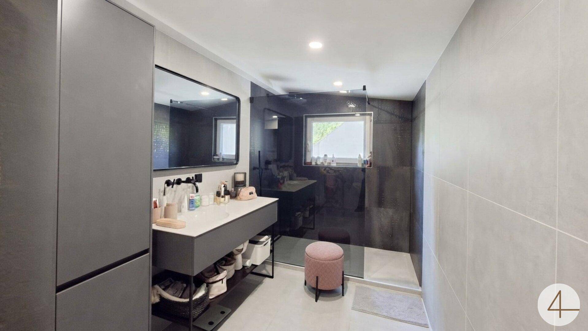 Modernes Badezimmer mit begehbarer Dusche, Doppelwaschbecken und großen grauen Fliesen.