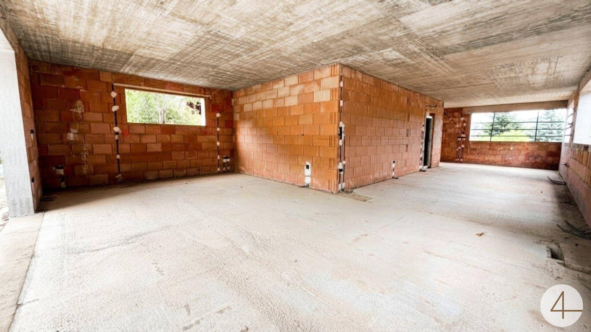 Unfertiger Innenraum eines Neubaus mit sichtbaren Ziegelwänden und Betonböden.