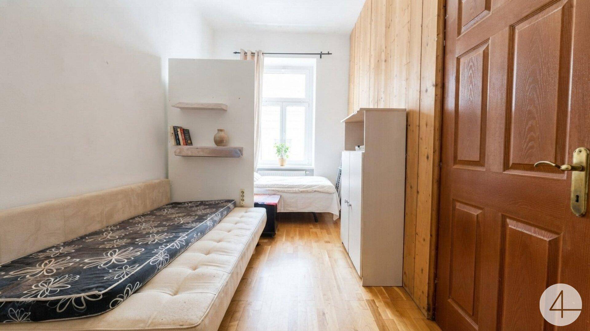 Helles Schlafzimmer mit zwei Betten, Holzvertäfelung und einem Fenster für natürliches Licht.