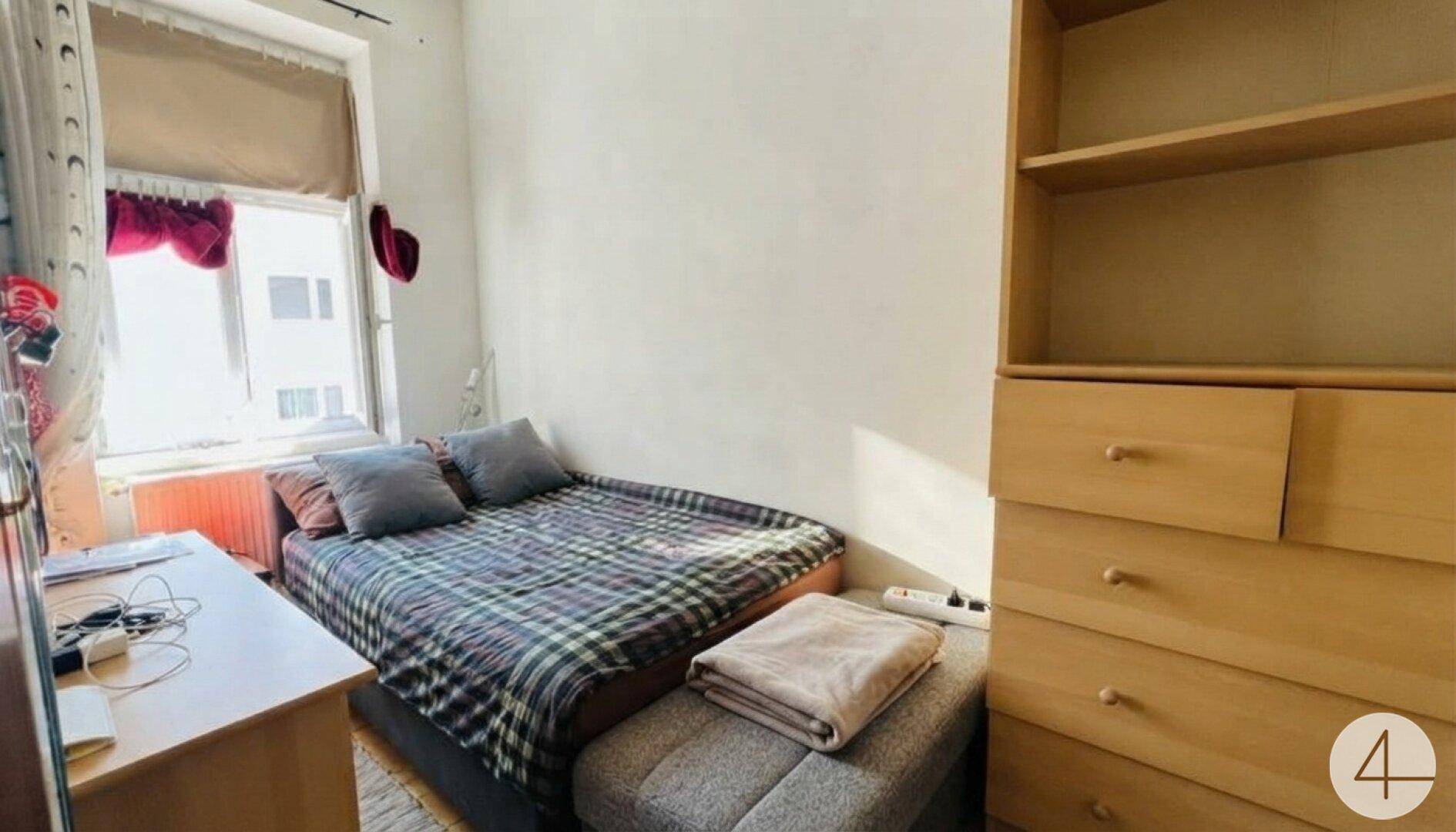 Gemütliches Schlafzimmer mit Doppelbett, Schreibtisch und Holzregal neben dem Fenster.