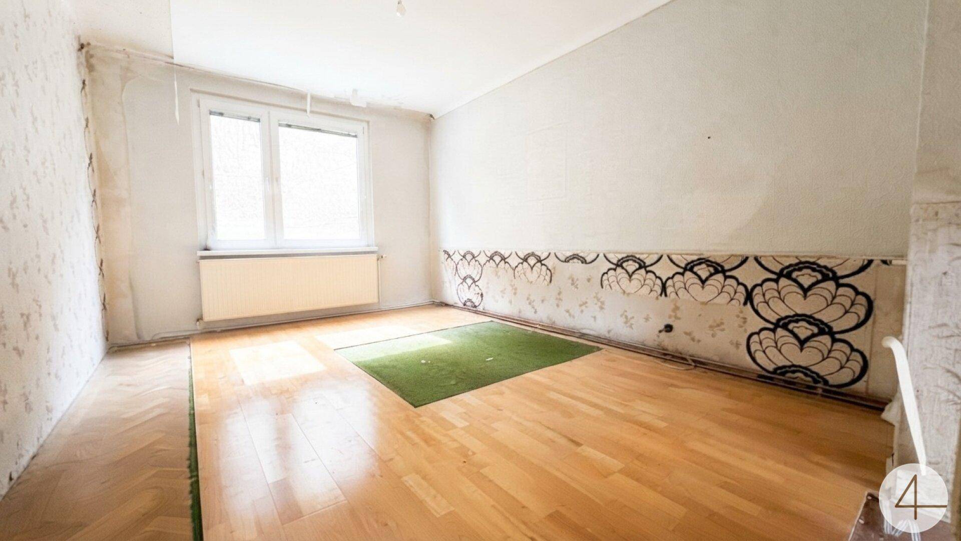 Schlafzimmer mit Parkettboden, dekorativer Tapete und einem Fenster für natürliches Licht.