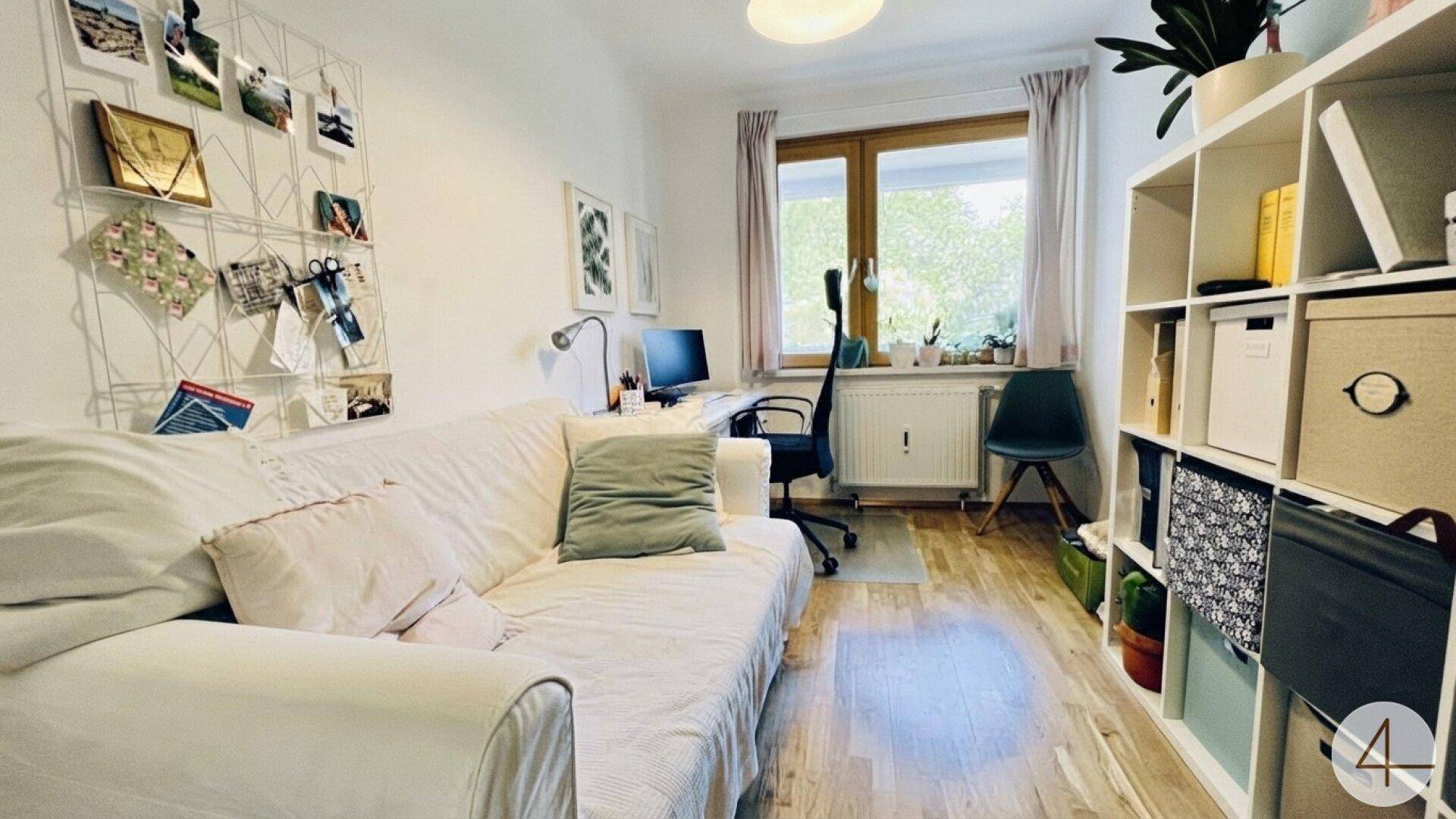 Helles Arbeitszimmer mit Schreibtisch, Regalen und gemütlichem Sofa.
