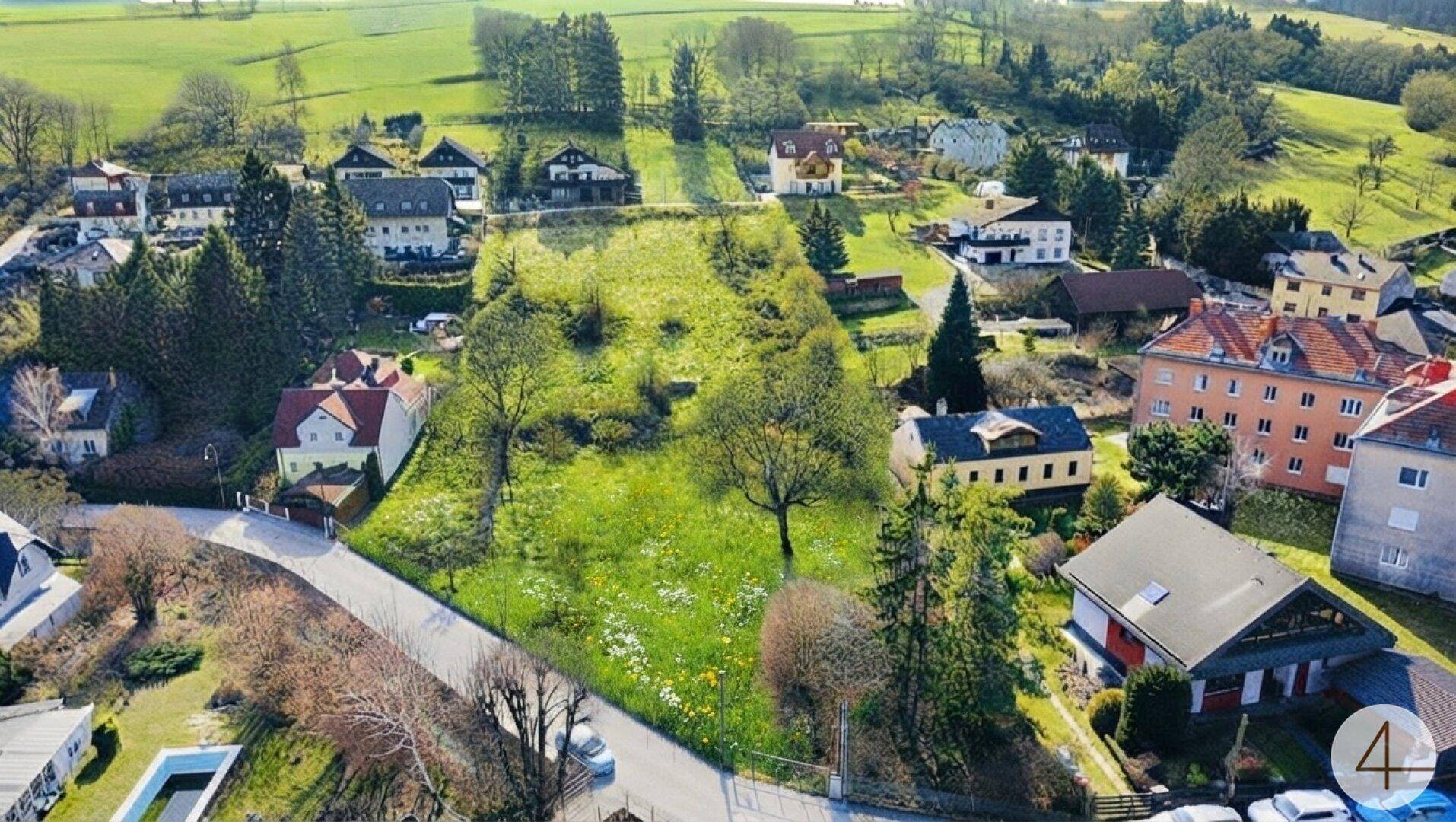 Luftaufnahme eines großen Grundstücks in ländlicher Umgebung, umgeben von Wohnhäusern und viel Grün.