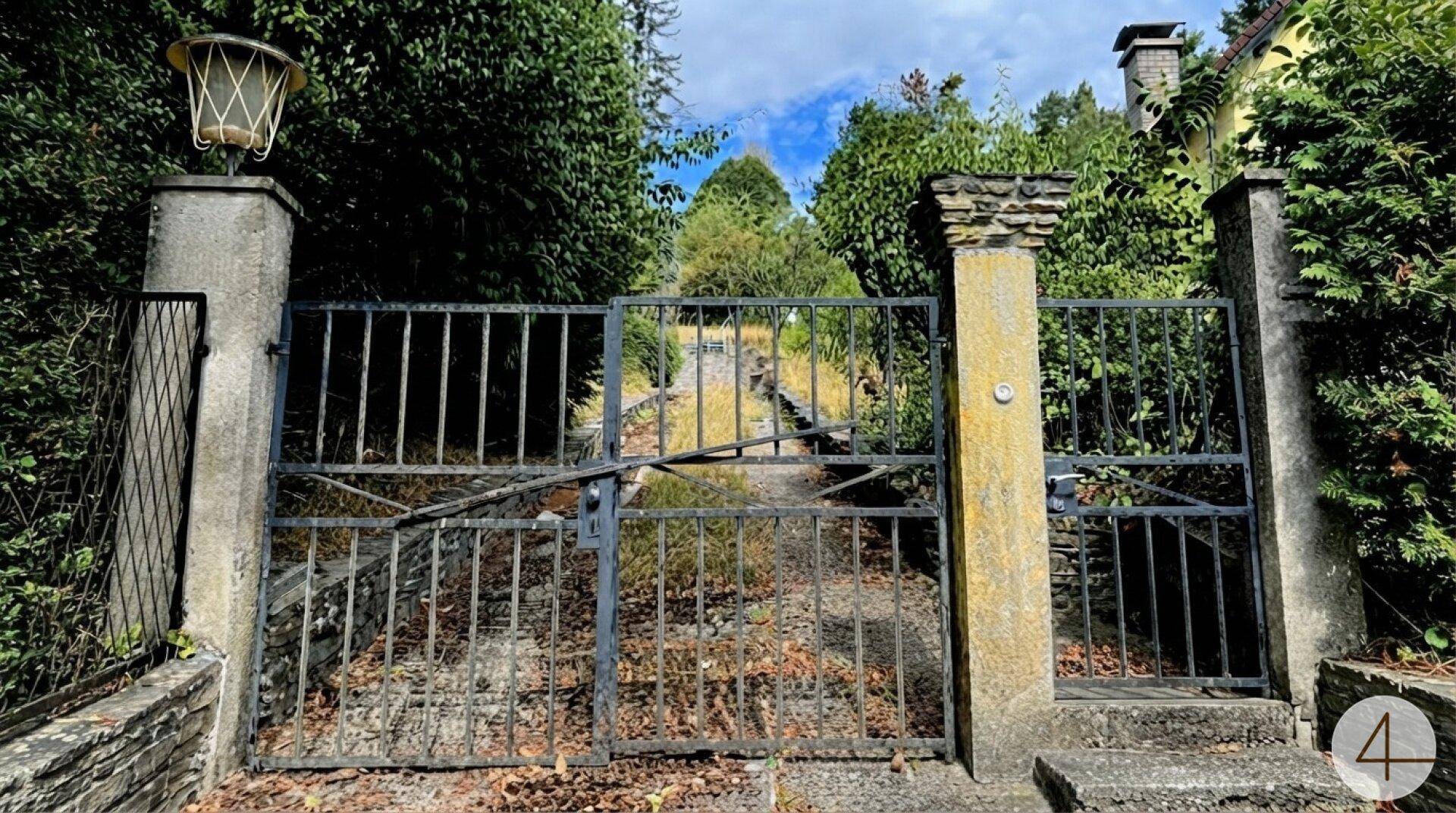 Historisches schmiedeeisernes Tor mit Steinsäulen als Zugang zum Grundstück.