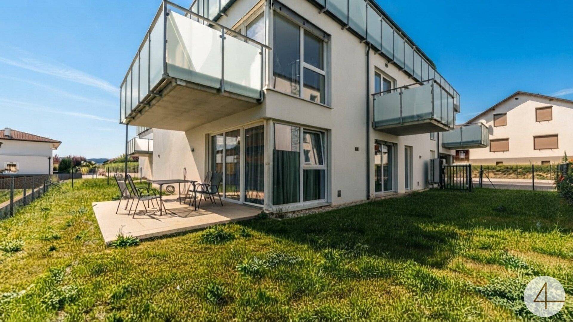 Moderne Wohnanlage mit mehreren Balkonen, einer Terrasse und einer gepflegten Rasenfläche.