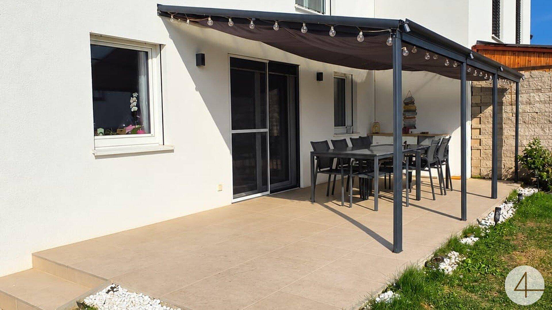 Überdachte Terrasse mit großem Esstisch und Stühlen, ideal für Mahlzeiten im Freien am Haus.