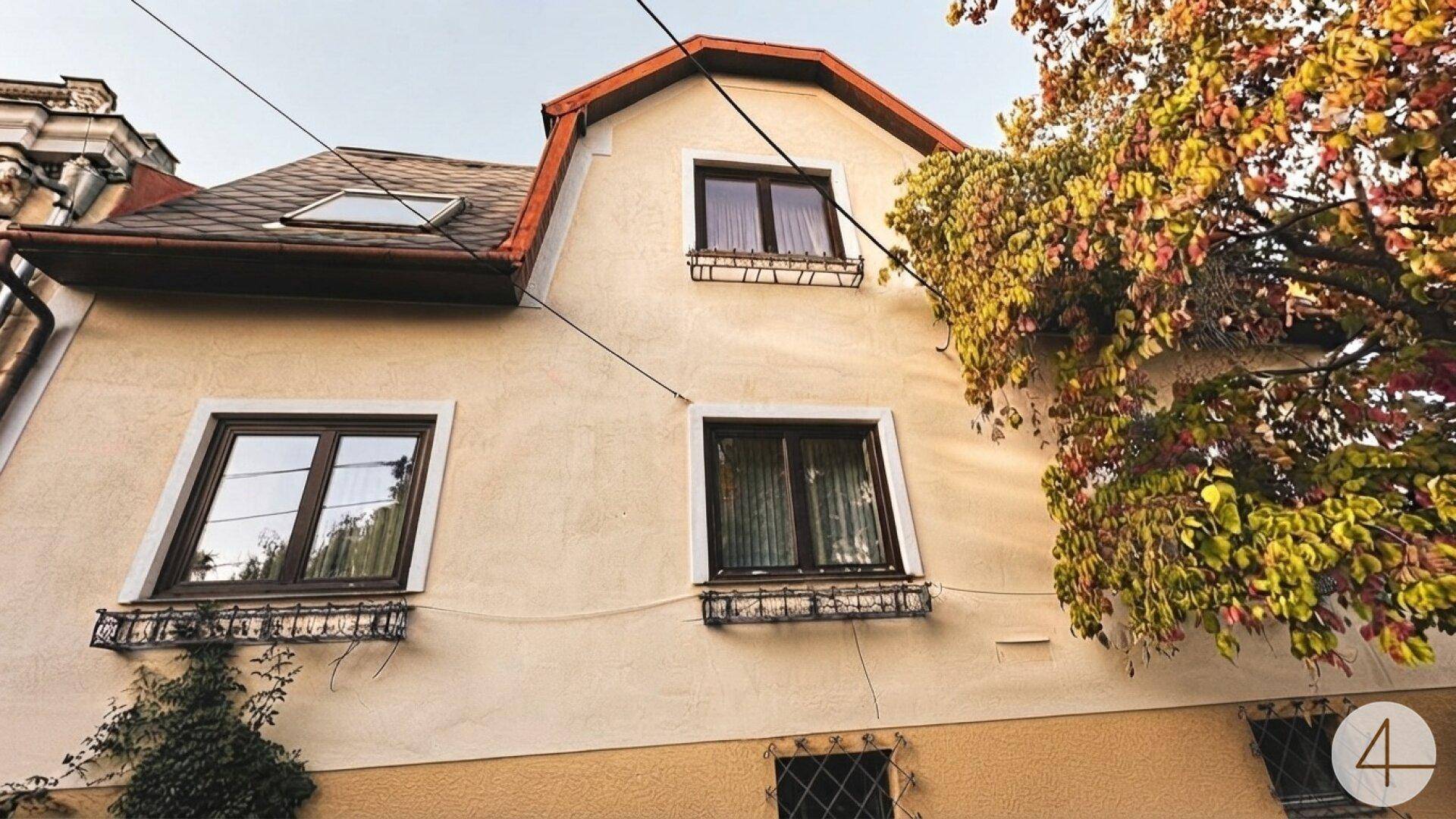 Seitenansicht des Hauses mit Mansarddach, Gaubenfenstern und herbstlicher Bepflanzung.