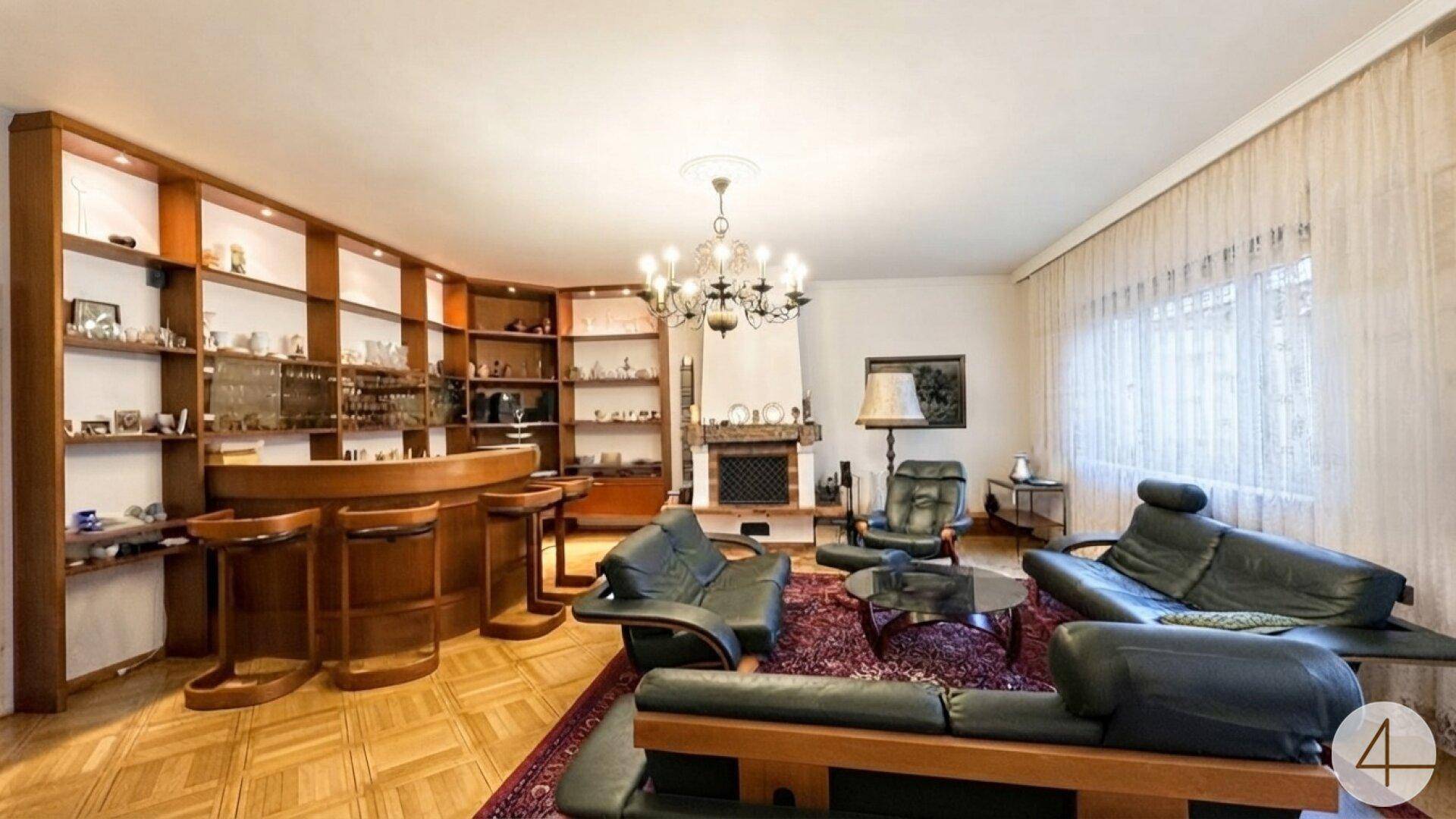Gemütliches Wohnzimmer mit Kamin, Parkettboden und einer integrierten Bar.