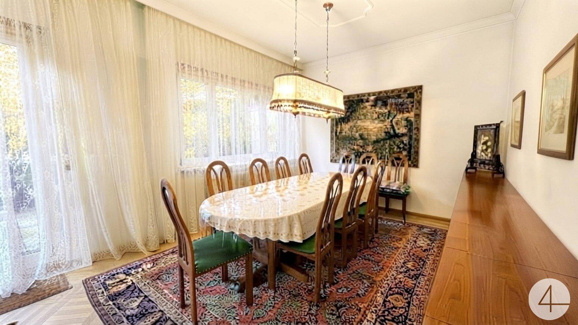 Eleganter Essbereich mit großem Holztisch, Teppich und Zugang zum Garten.