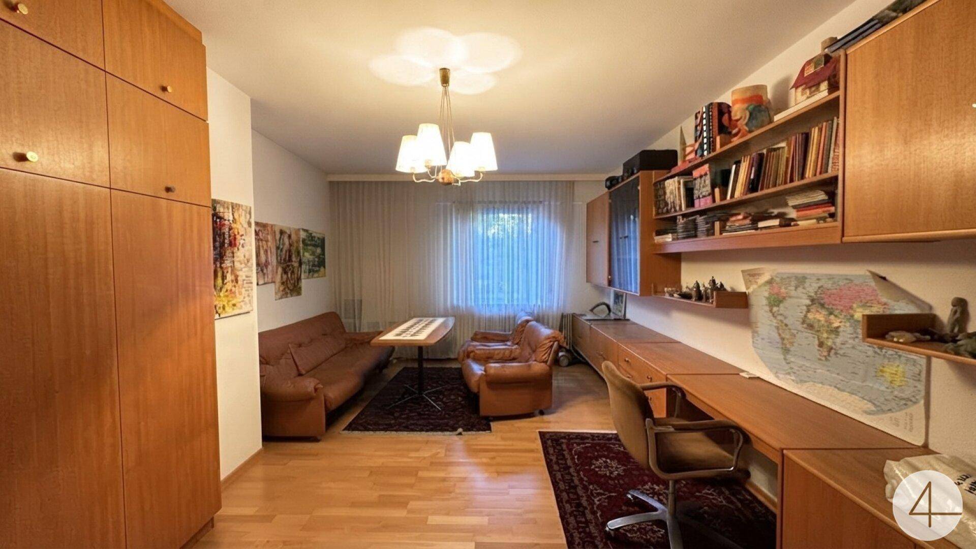 Gemütliches Wohnzimmer mit Holzmöbeln, Teppich und Blick in den Garten.