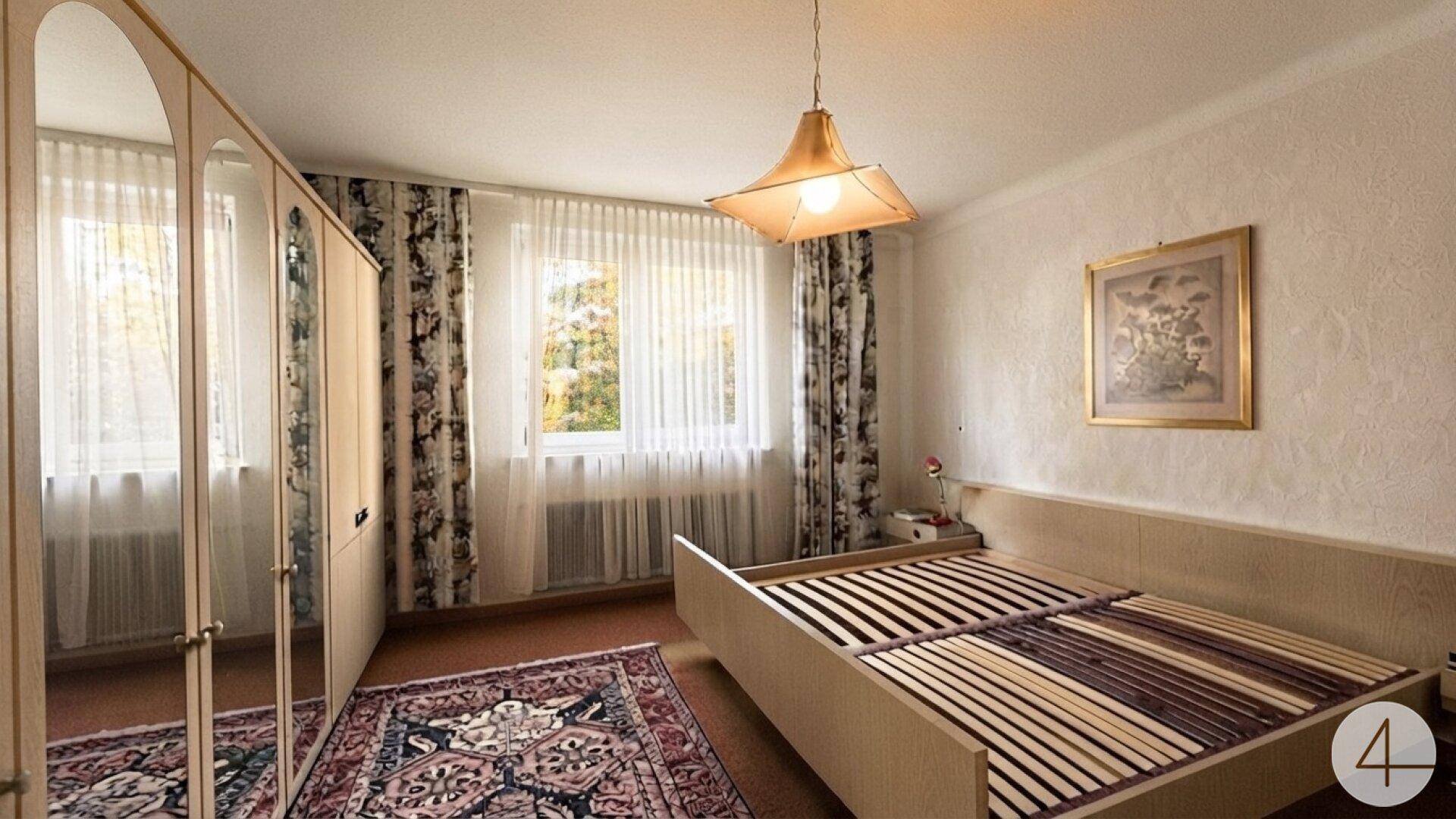 Helles Schlafzimmer mit Doppelbett, Teppich und Blick ins Grüne.