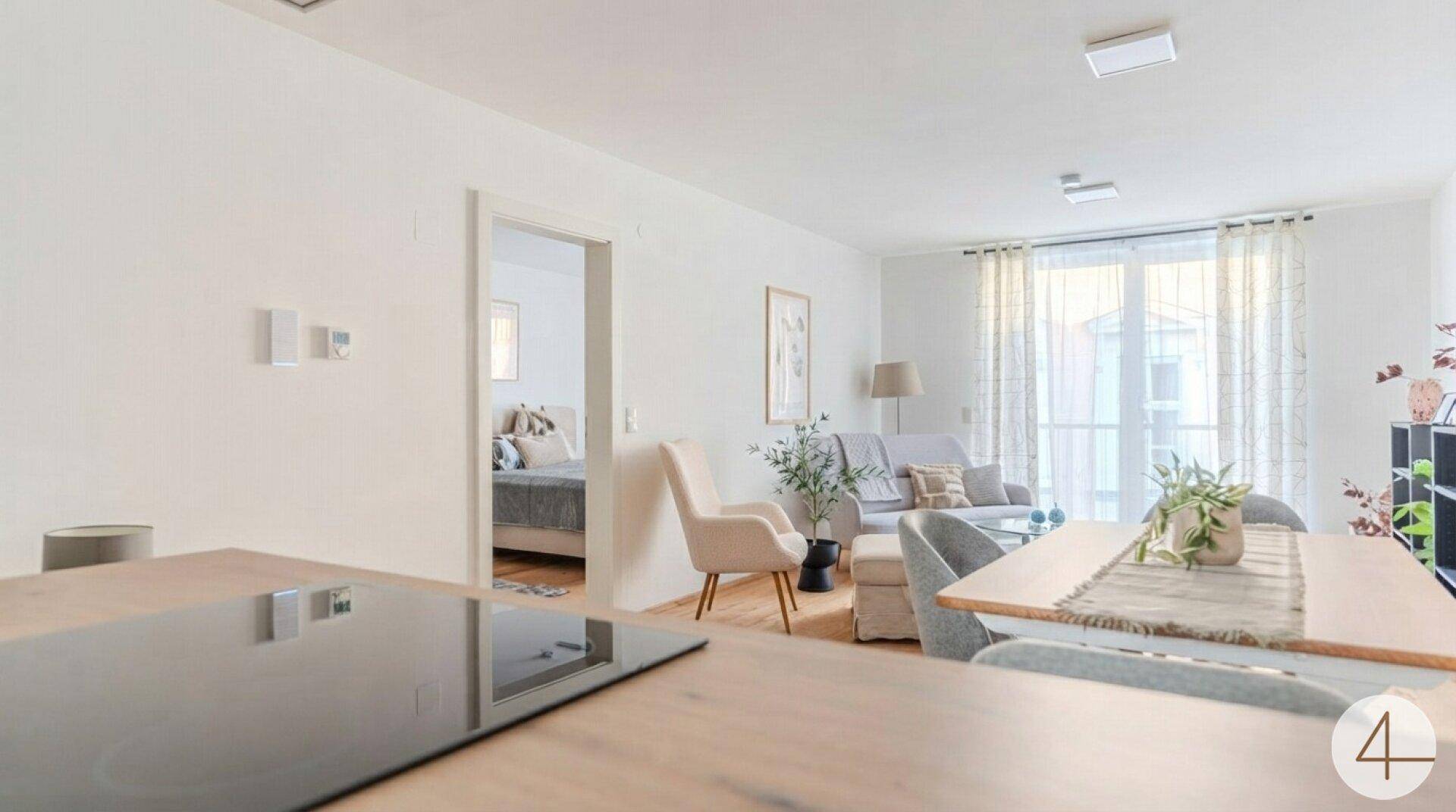 Heller Wohn- und Essbereich mit offener Gestaltung und Blick in ein angrenzendes Schlafzimmer.