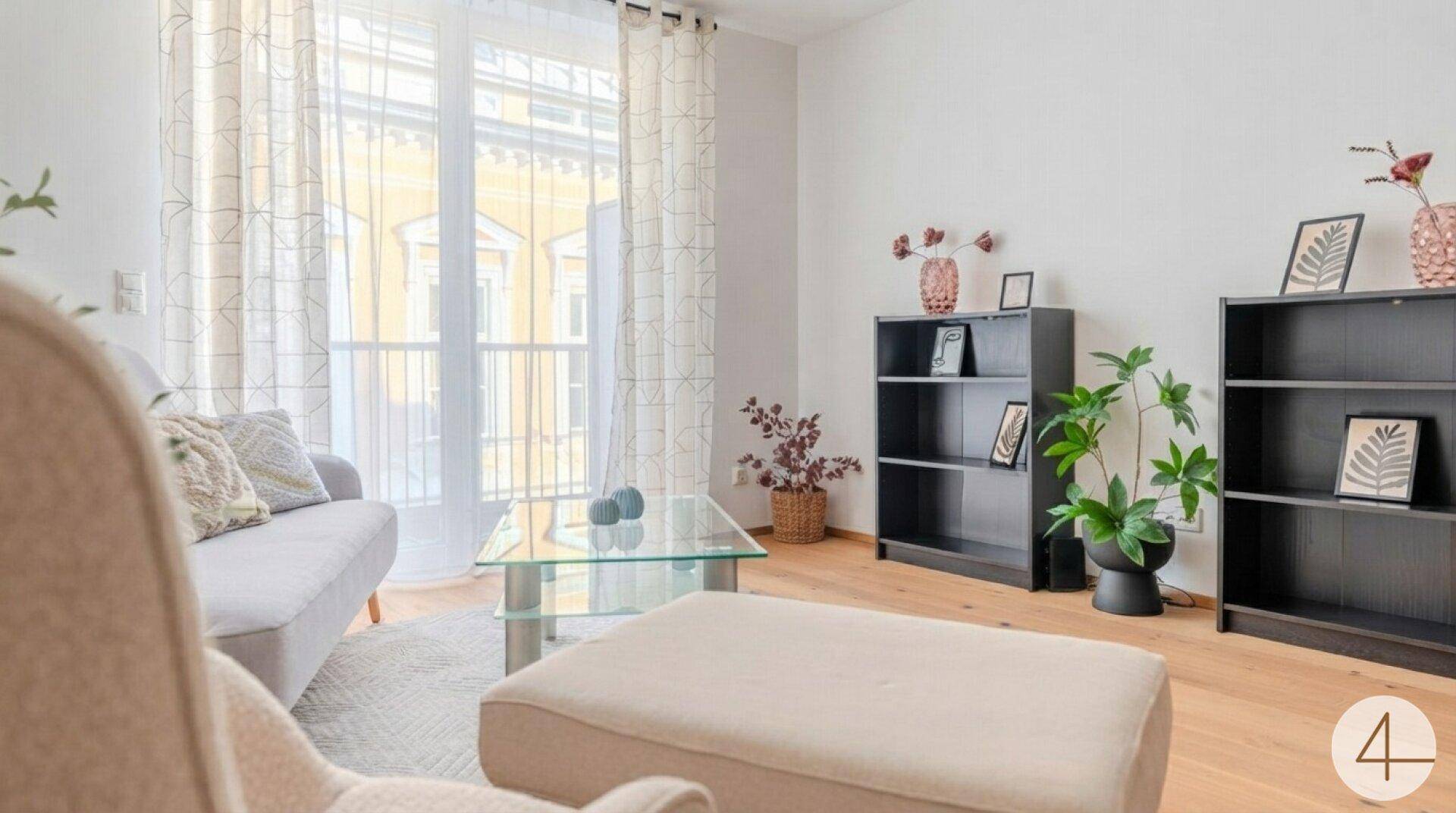 Gemütliches Wohnzimmer mit beigem Sessel, Couch und Zugang zu einem sonnigen Balkon.