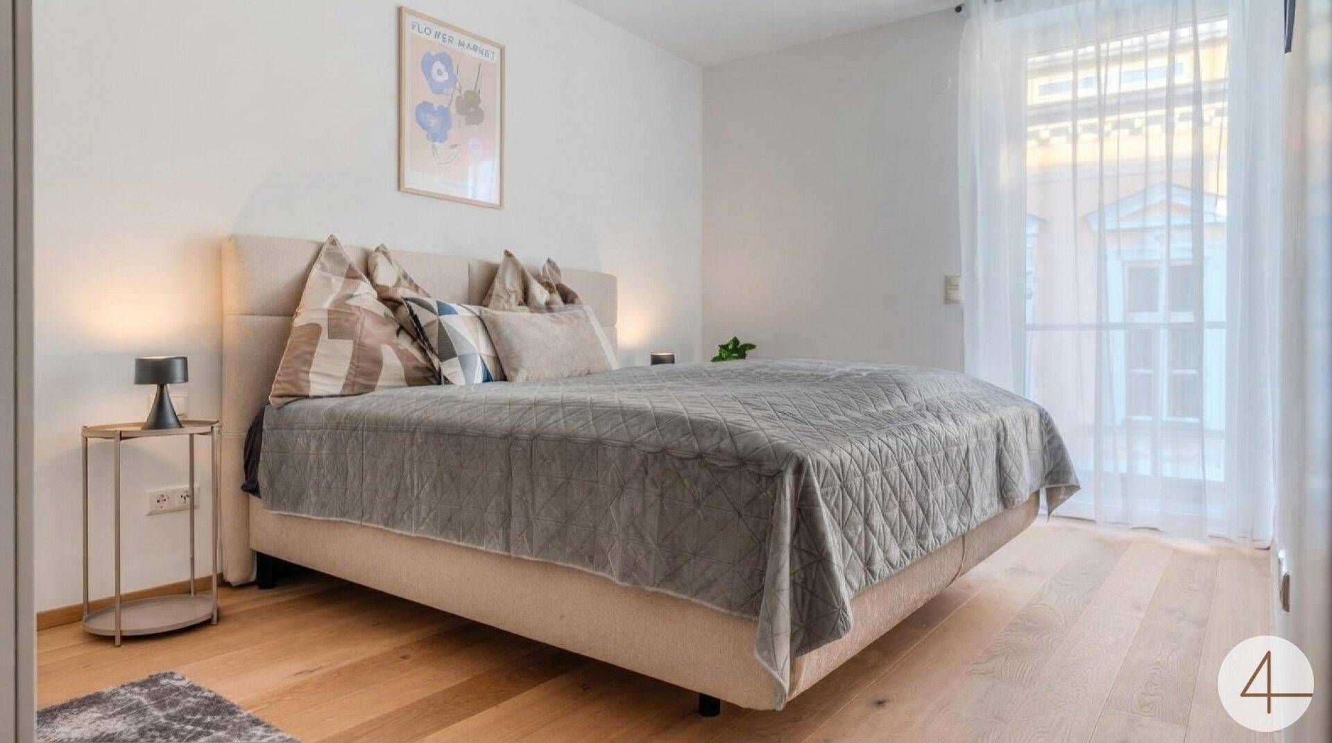 Modernes Schlafzimmer mit großem Doppelbett, Nachttisch und viel natürlichem Licht.