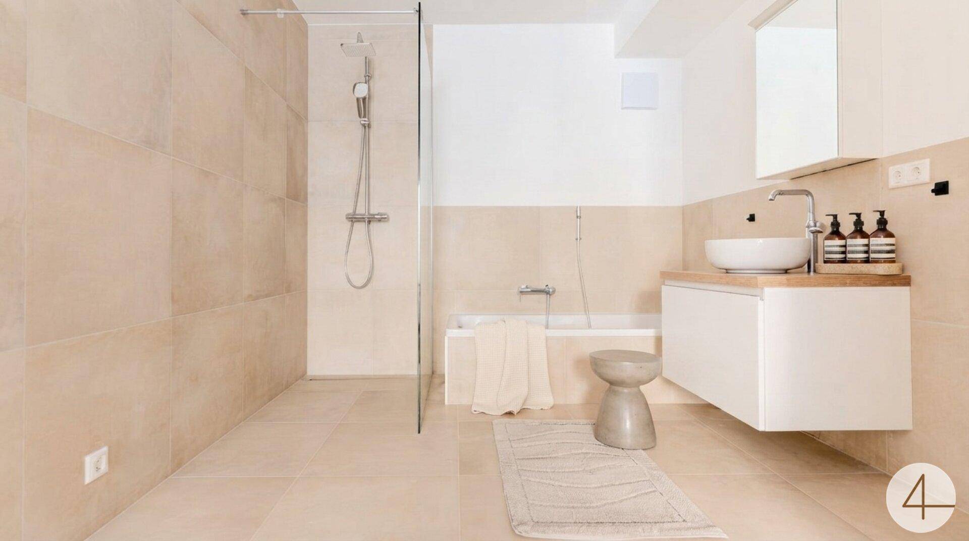 Modernes Badezimmer mit beigen Fliesen, begehbarer Dusche und Badewanne.