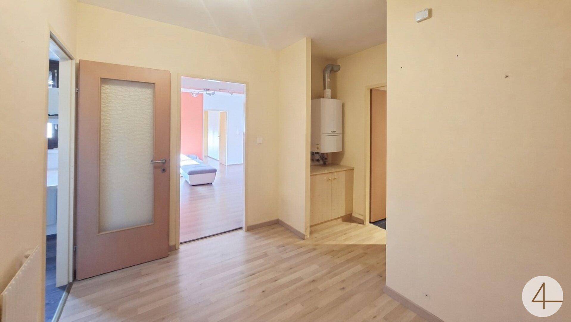 Heller Flur mit Holzfußboden und Zugang zu weiteren Räumen, inklusive Warmwasserbereiter.