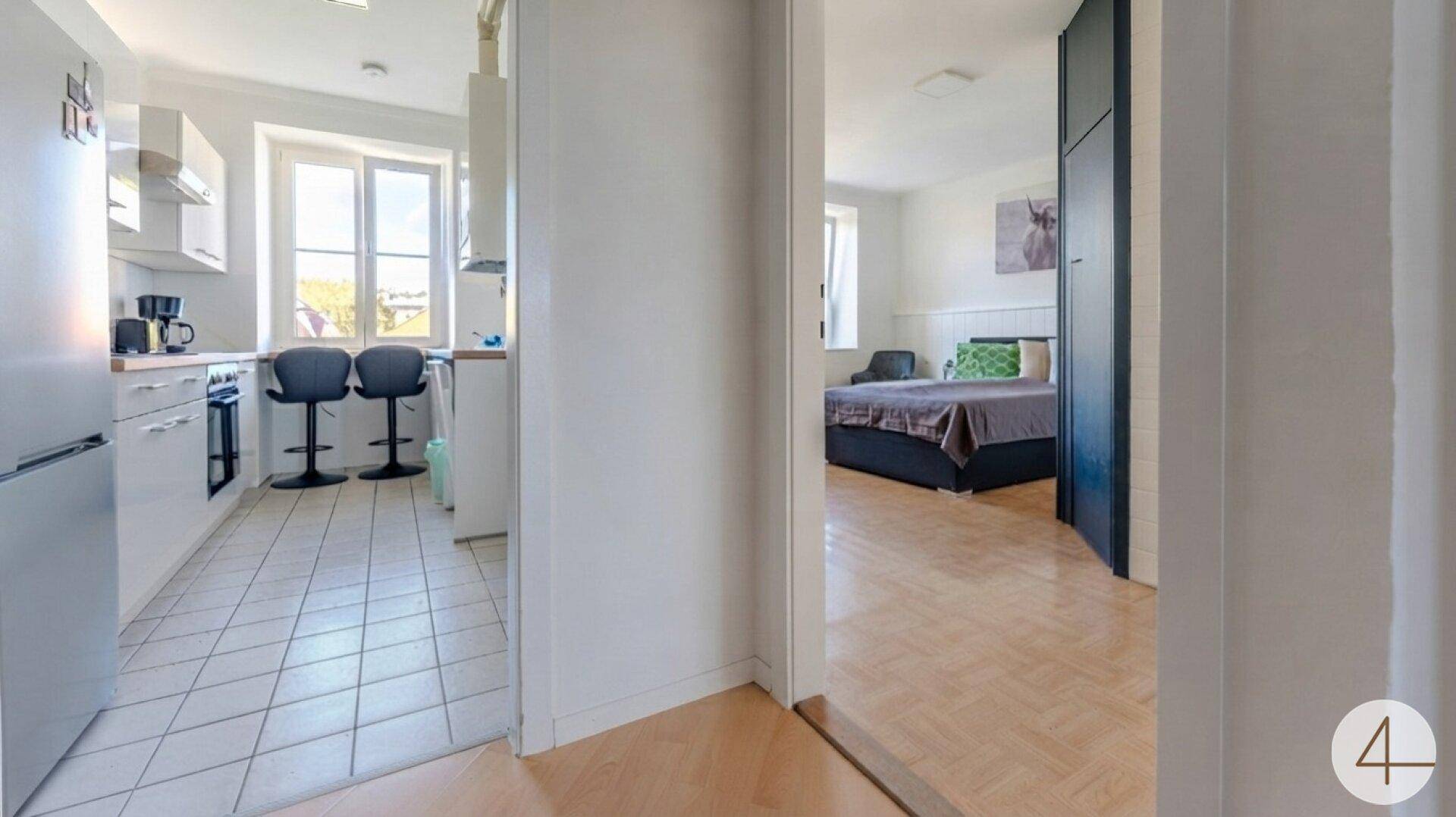 Flur mit Holzfußboden und Zugang zur Küche sowie einem Schlafzimmer.
