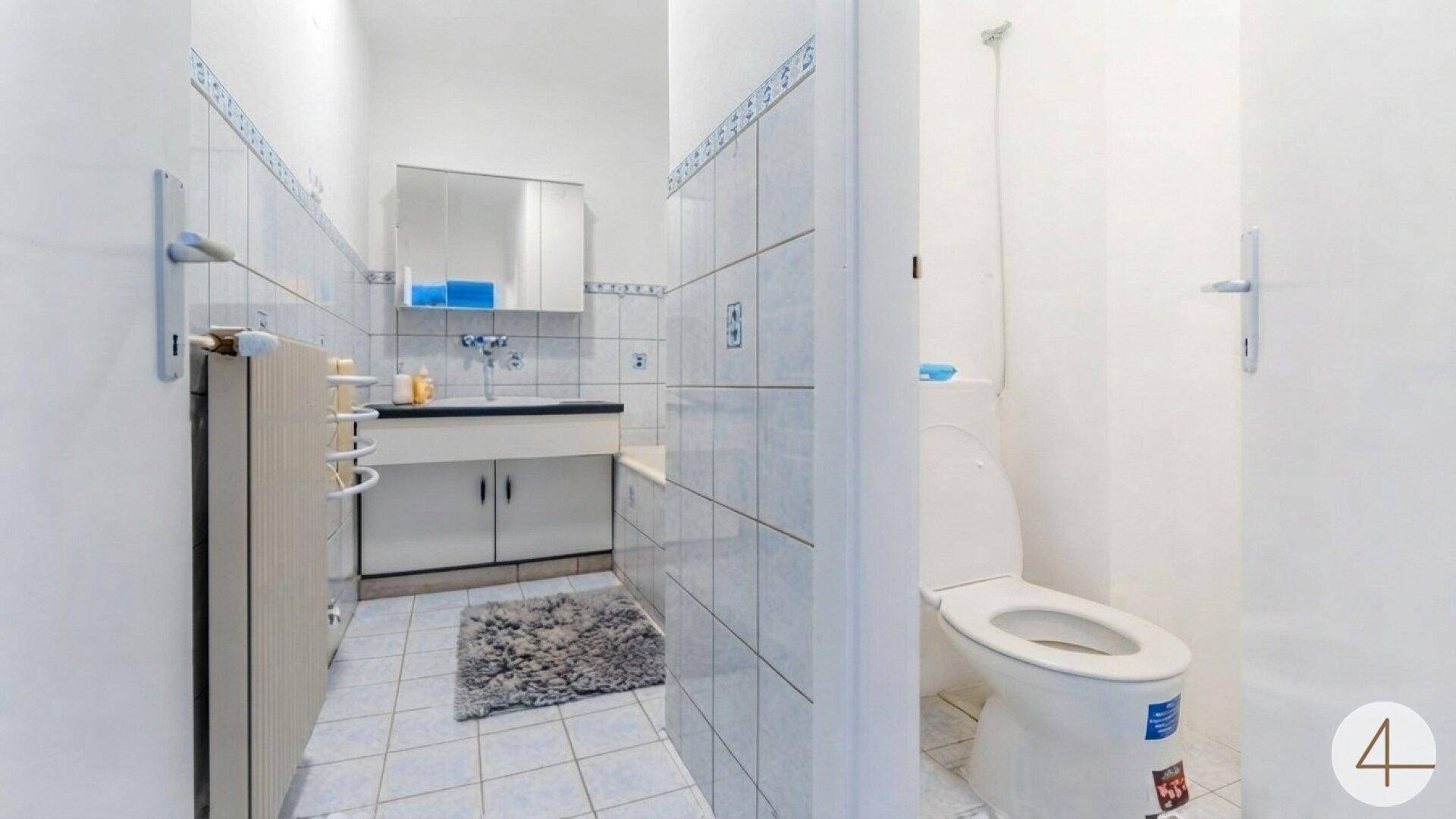 Badezimmer mit Toilette, Badewanne, Waschbecken und Spiegelschrank.