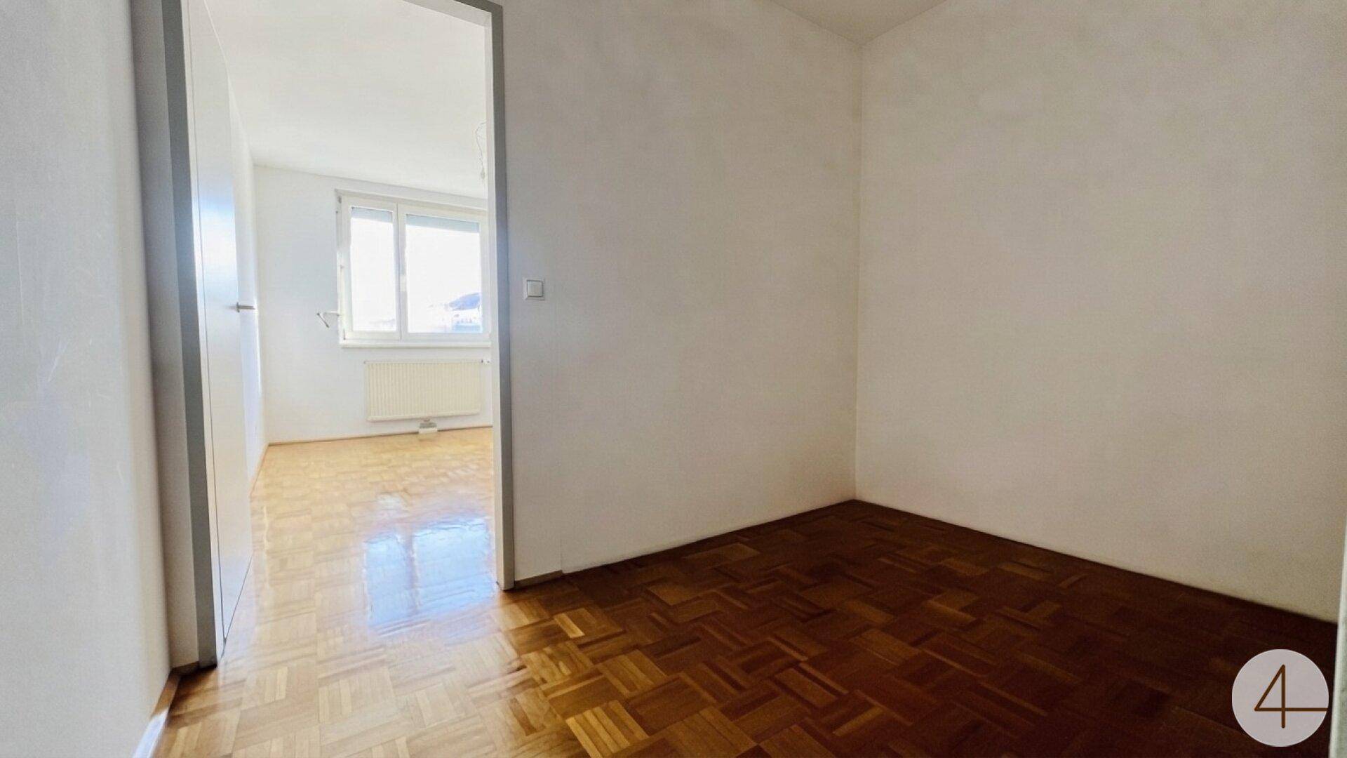 Heller Flur mit Parkettboden, der zu einem weiteren Zimmer führt.