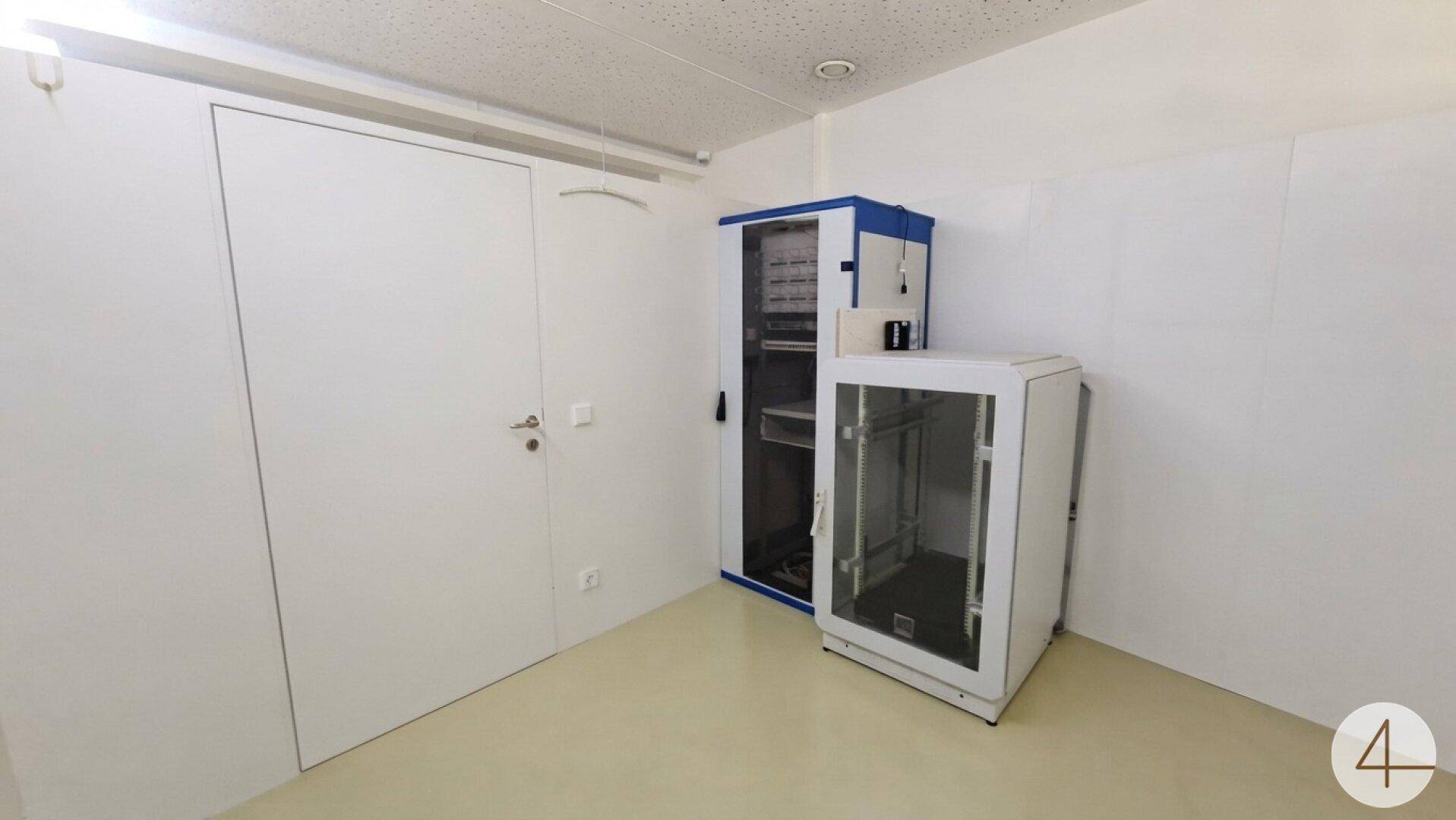 Abstellraum mit weißen Wänden und zwei Serverschränken, ideal für technische Ausstattung.