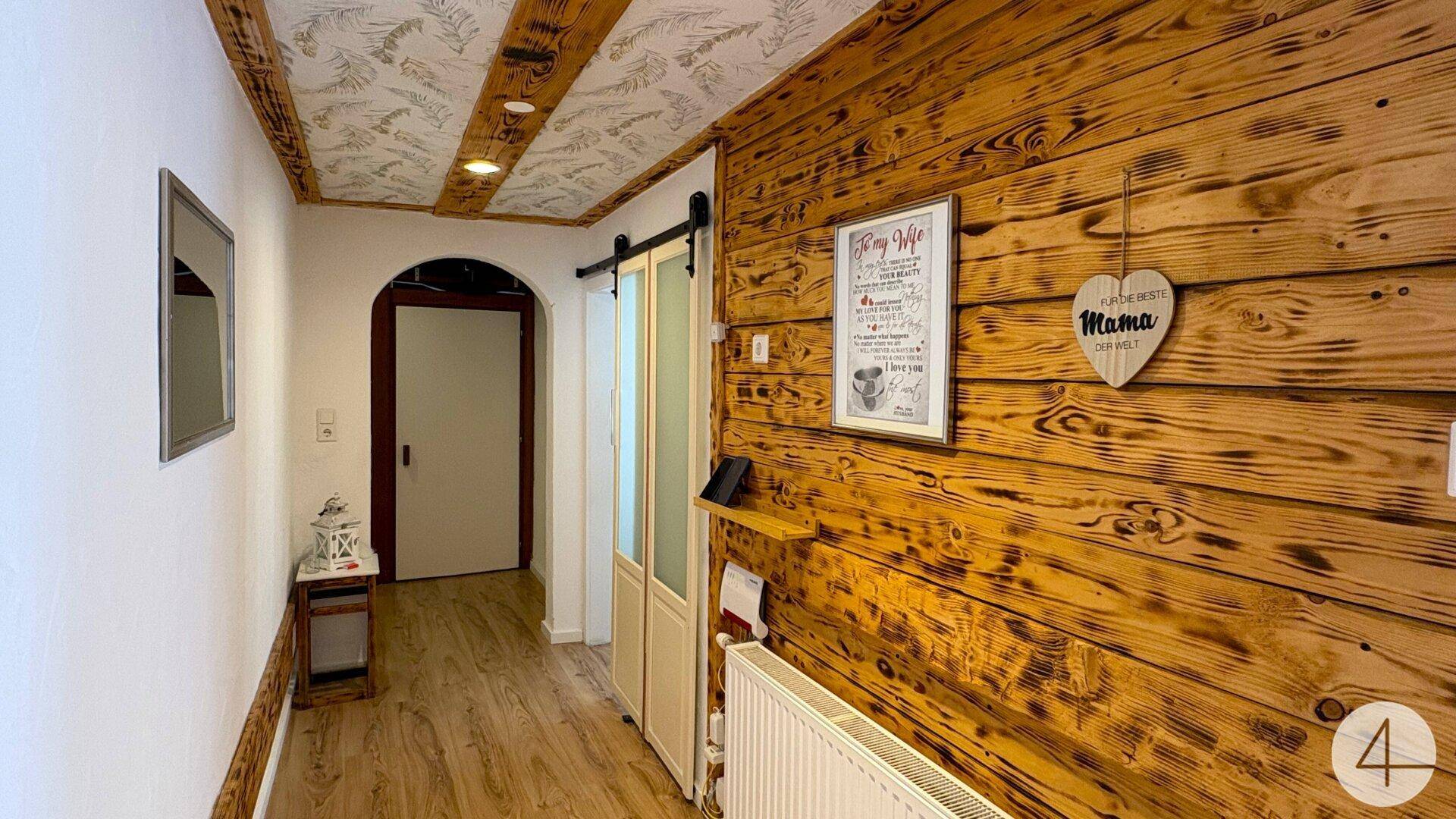 Gemütlicher Flur mit Holzwandverkleidung und einer Decke mit Holzbalken und Tapetenmuster.