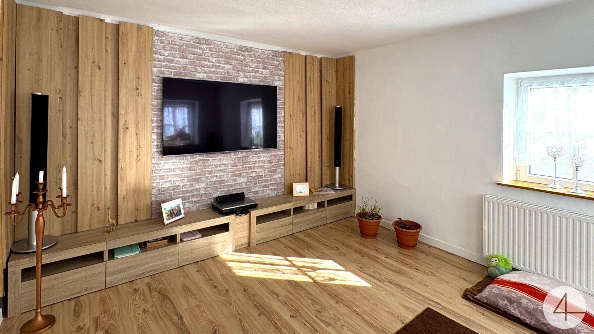 Moderner Wohnbereich mit Holzwandverkleidung, Ziegelakzentwand und großem Flachbildfernseher.