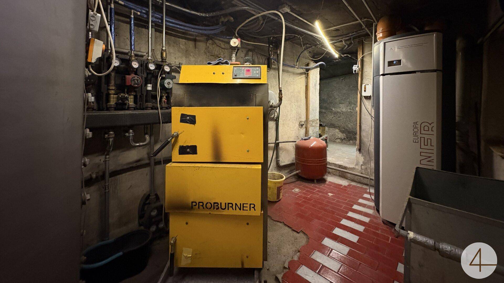 Heizungsraum im Keller mit einem Proburner-Kessel und verschiedenen Installationen.