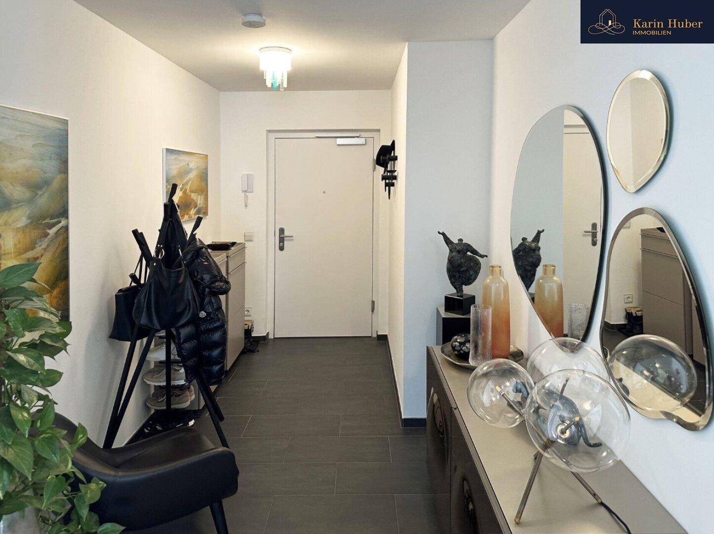 Moderner Eingangsbereich mit dunklen Fliesen, stilvollen Spiegeln und Garderobe.