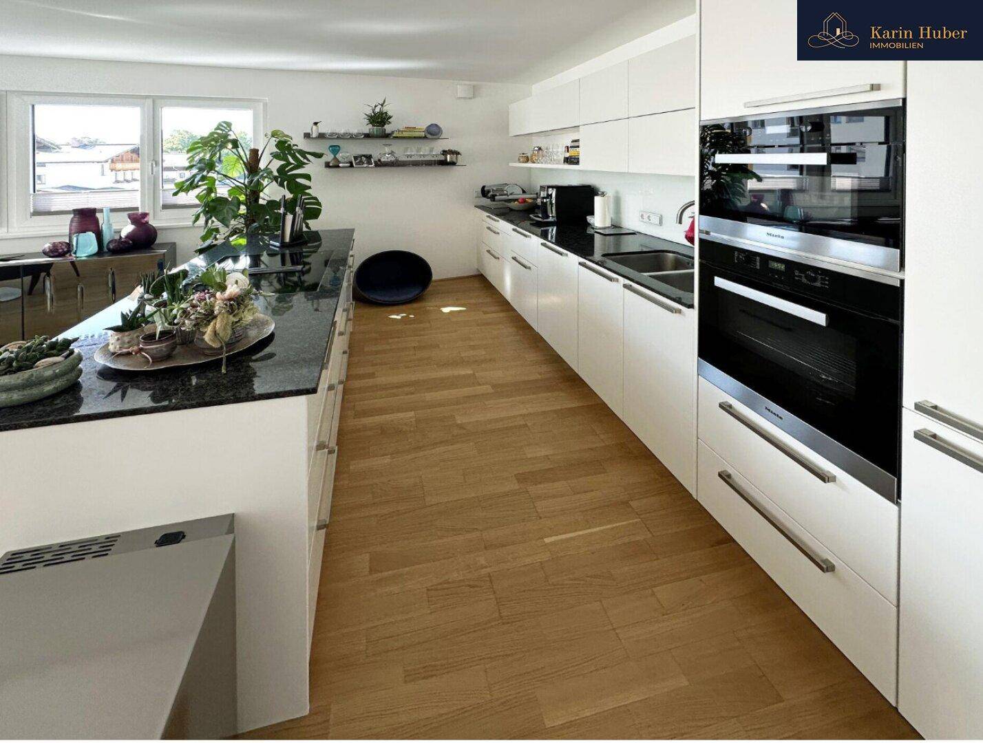 Helle, moderne Küche mit weißen Schränken, dunkler Granitarbeitsplatte und Holzboden.