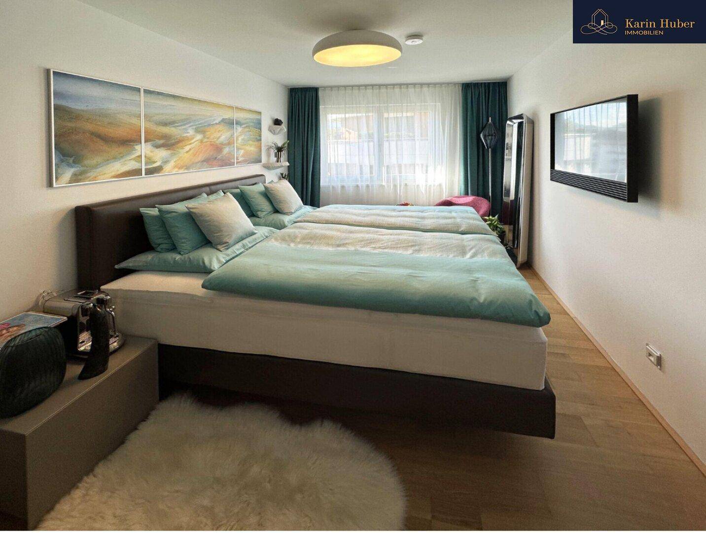 Gemütliches Schlafzimmer mit Doppelbett, Holzboden und großen Fenstern für viel Tageslicht.