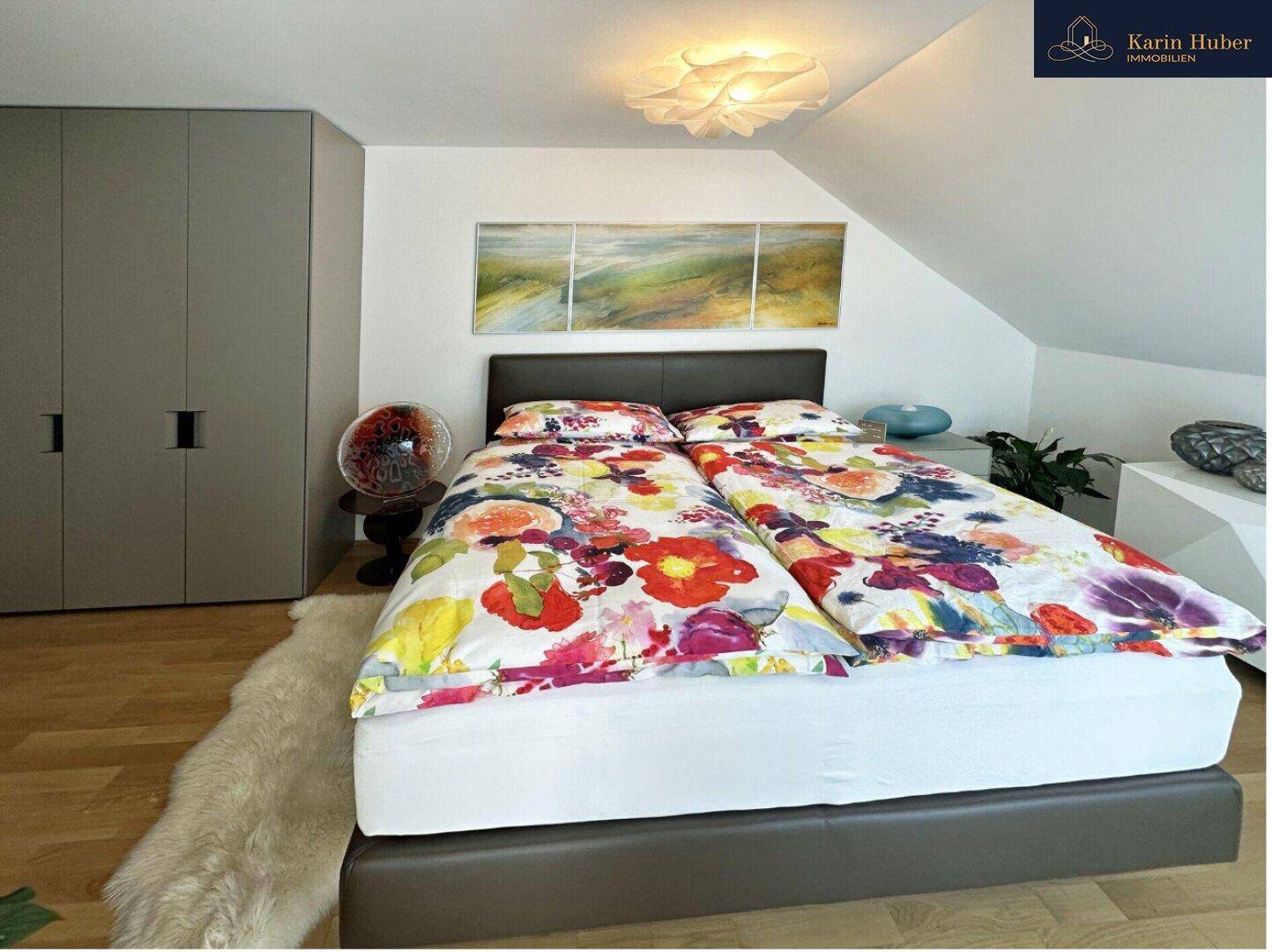 Helles Schlafzimmer mit Dachschräge, farbenfroher Bettwäsche und integrierten Kleiderschränken.