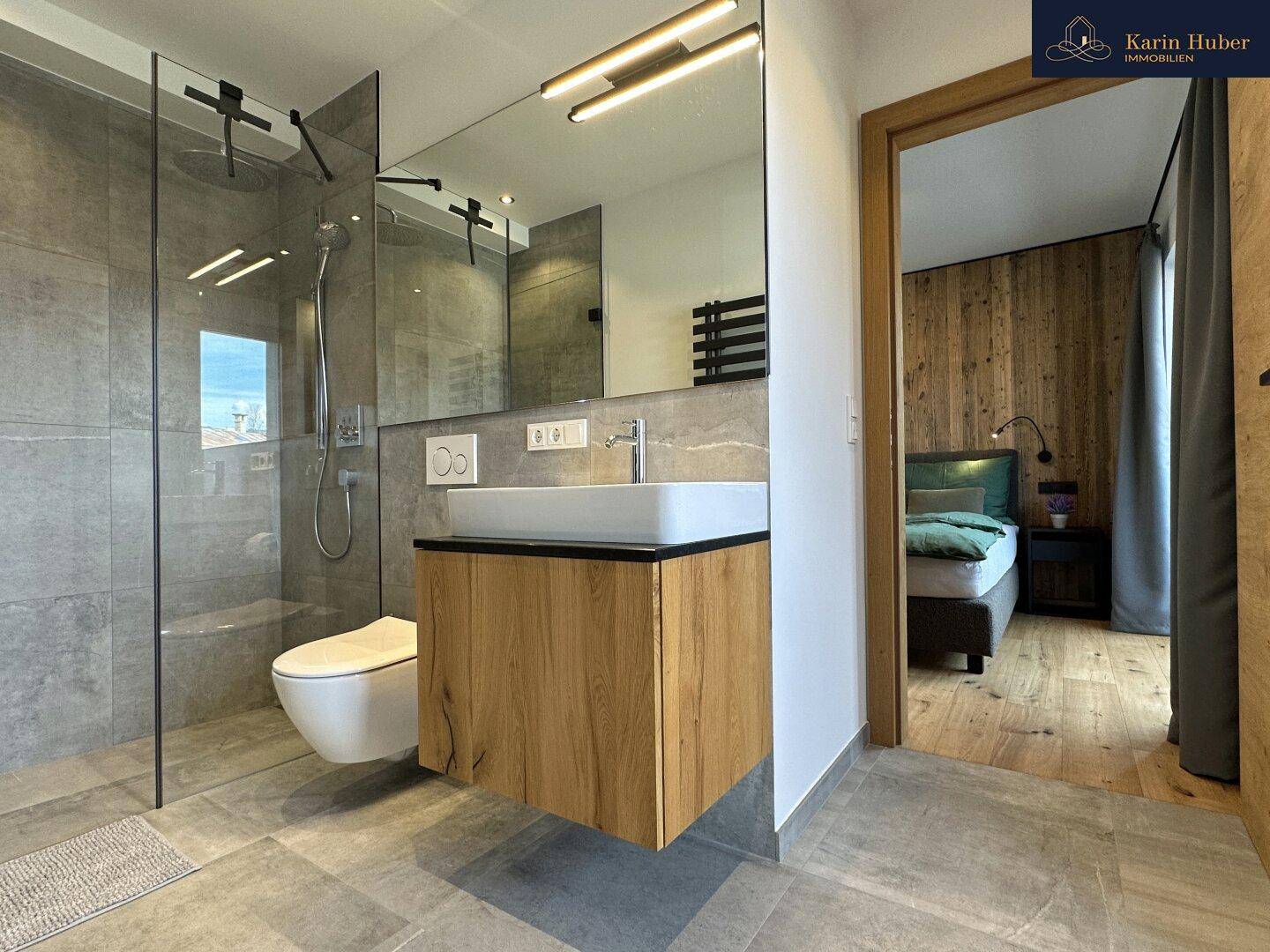 Modernes Badezimmer mit begehbarer Dusche, schwebendem Waschtisch und Blick ins Schlafzimmer.