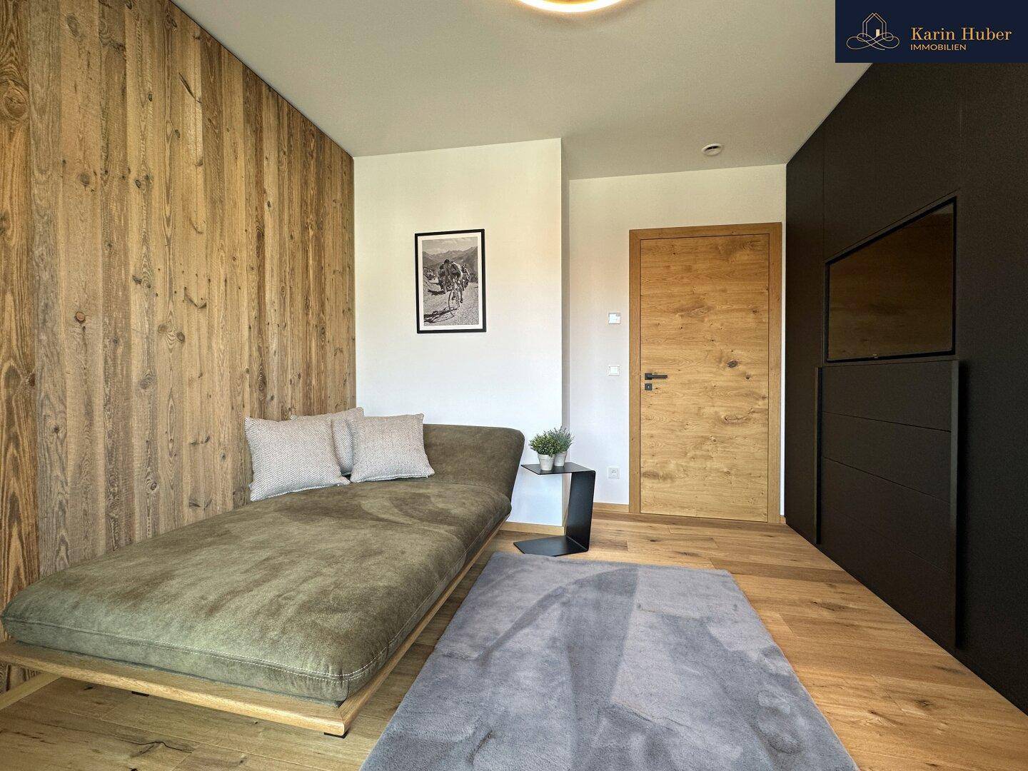 Entspannungsbereich oder Gästezimmer mit Holzwand, bequemer Liege und modernem Design.