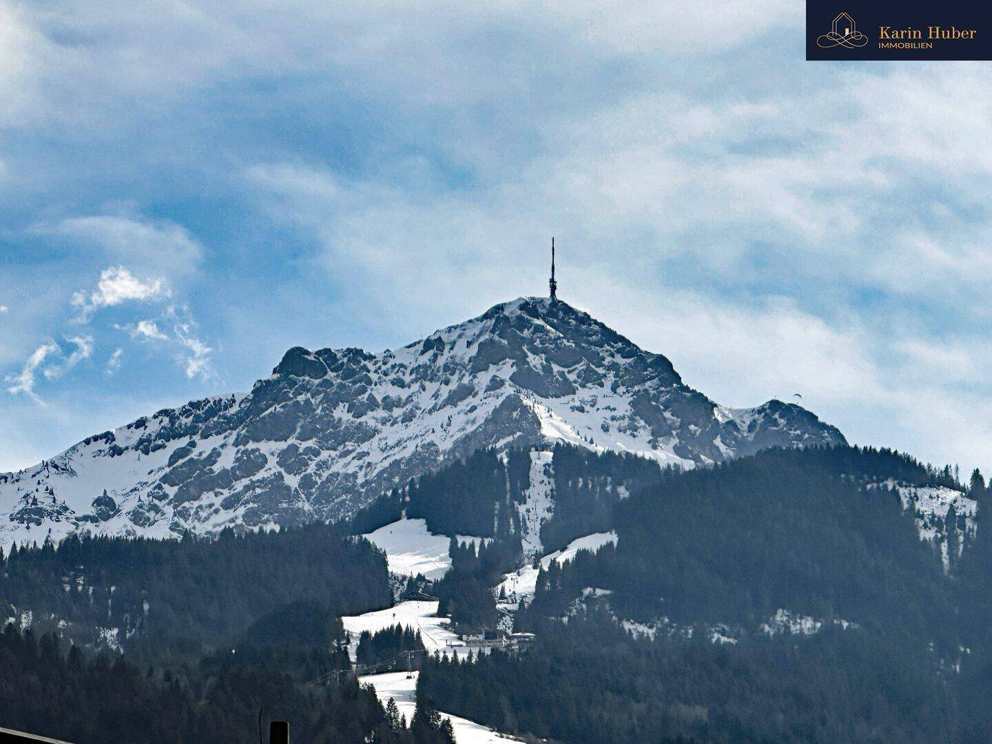 Panoramablick auf einen schneebedeckten Berg mit Sendemast unter blauem Himmel.
