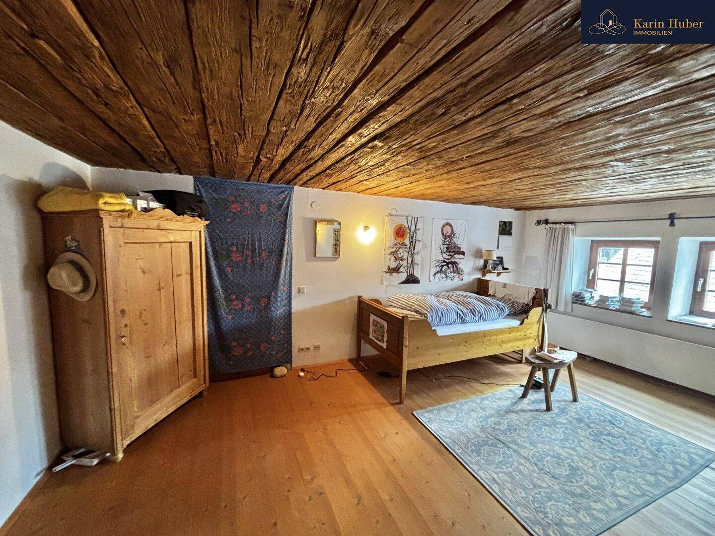 Schlafzimmer mit Holzboden, Holzbalkendecke und einem traditionellen Kleiderschrank.