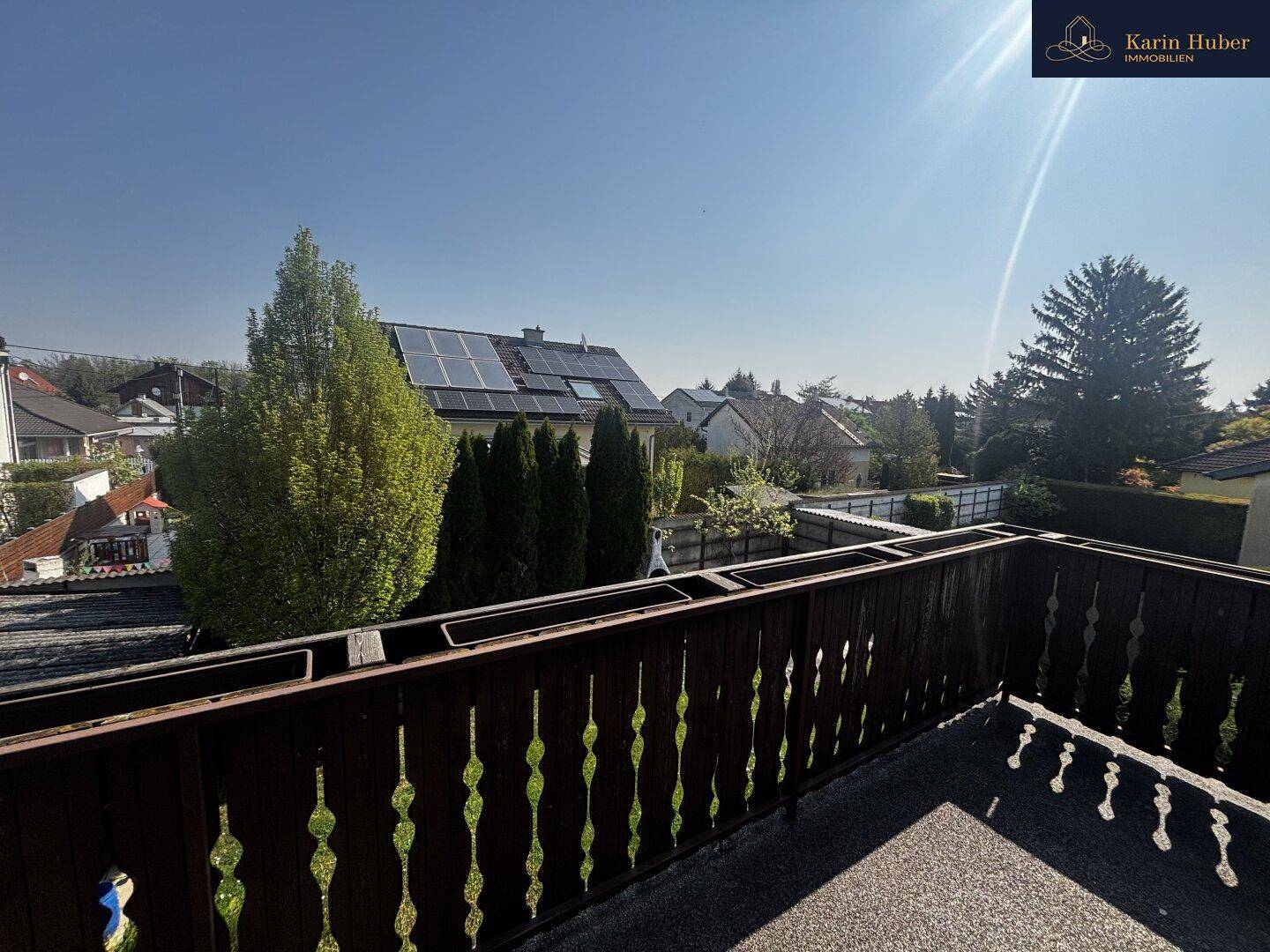 Balkon mit Holzbalkonbrüstung und Blick auf die umliegende Nachbarschaft mit Solaranlagen.