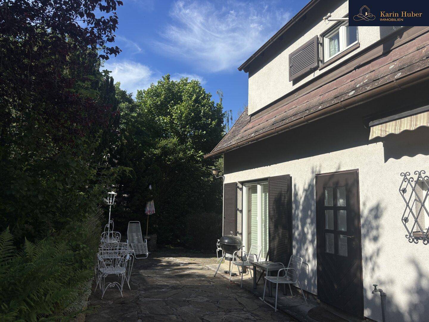 Gemütliche Steinterrasse mit Gartenmöbeln und Grillbereich, ideal für entspannte Stunden im Freien.