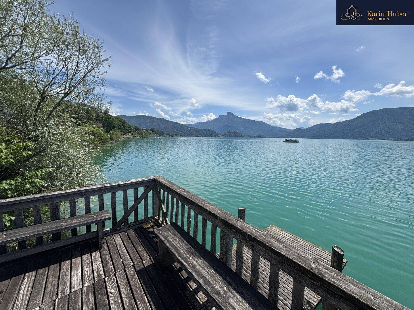 Geräumige Holzplattform mit Sitzbänken bietet einen atemberaubenden Panoramablick über den See und die Berge.