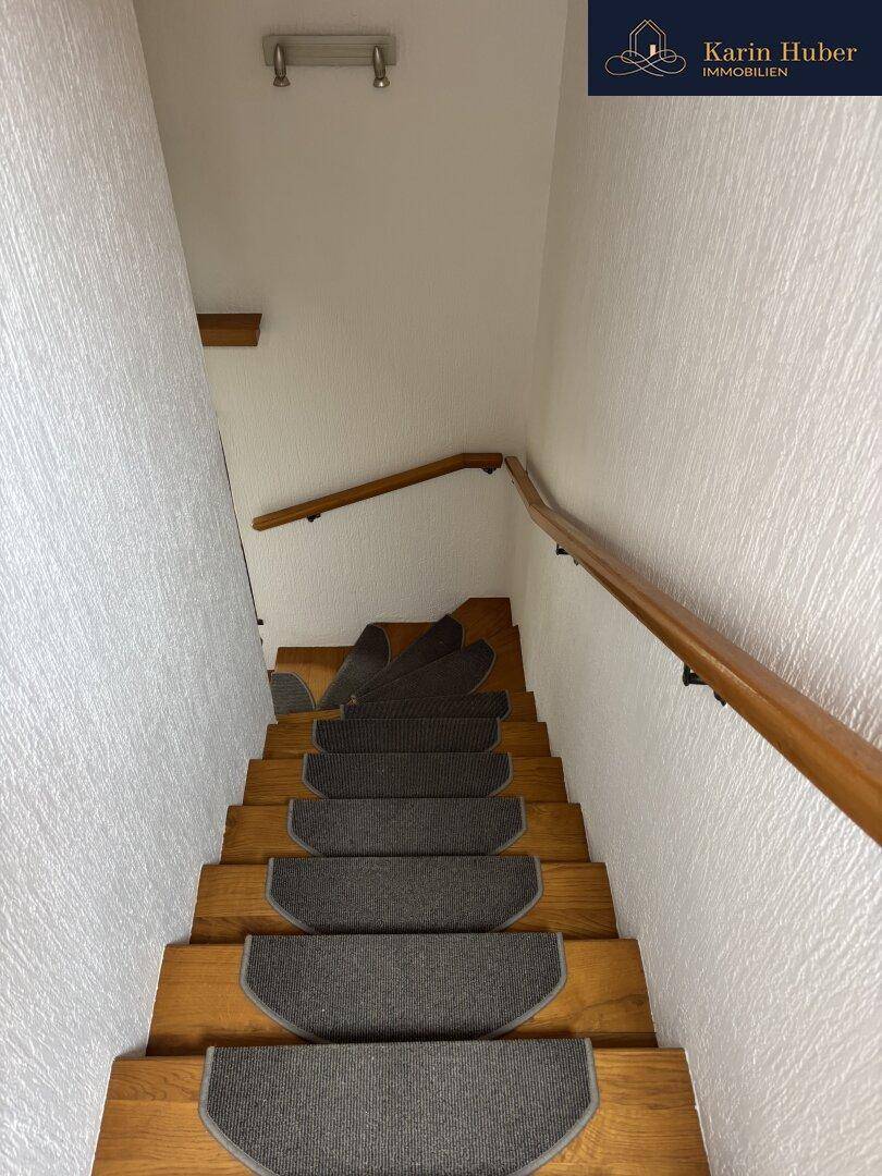 Holztreppe mit Teppichläufern und Handlauf, die die Stockwerke verbindet.