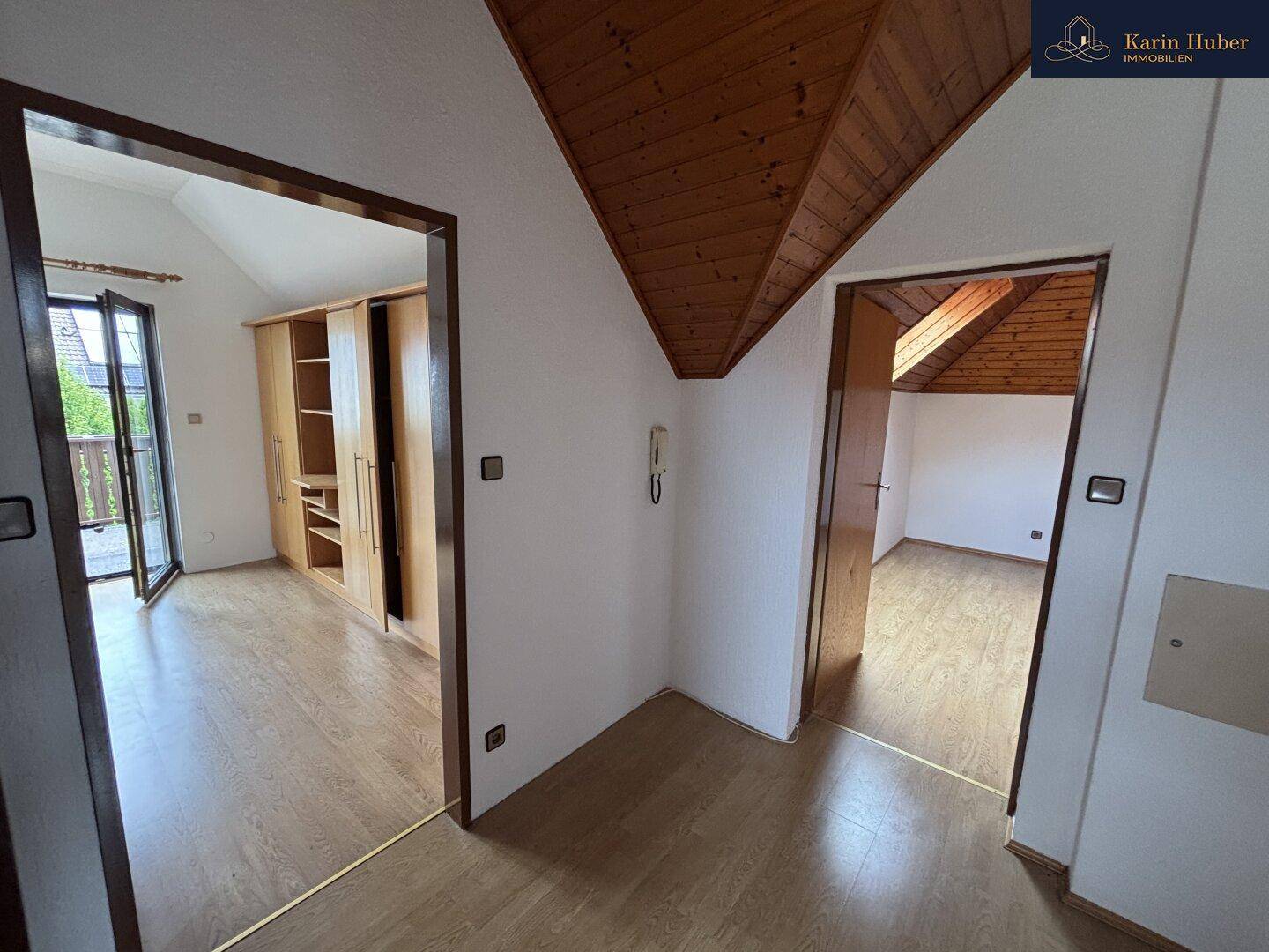 Flur im Dachgeschoss mit Holzdecke und Laminatboden, der zu mehreren Zimmern führt.
