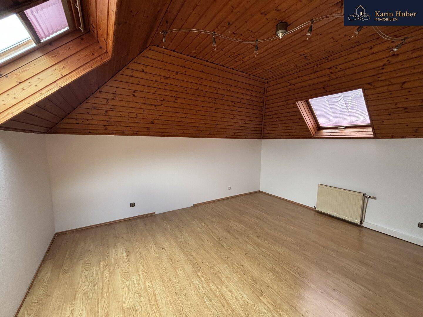 Gemütliches Zimmer im Dachgeschoss mit Holzdecke, Laminatboden und Dachfenster.