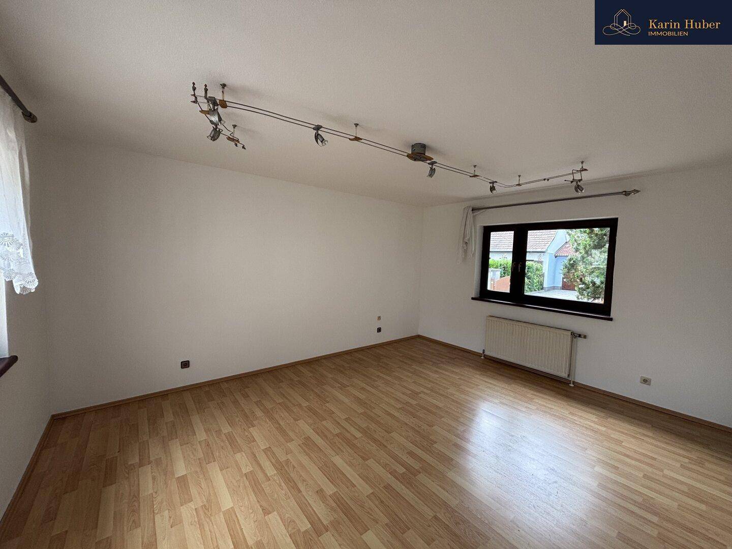 Helles Wohnzimmer mit Laminatboden und Heizkörper, bereit für individuelle Gestaltung.