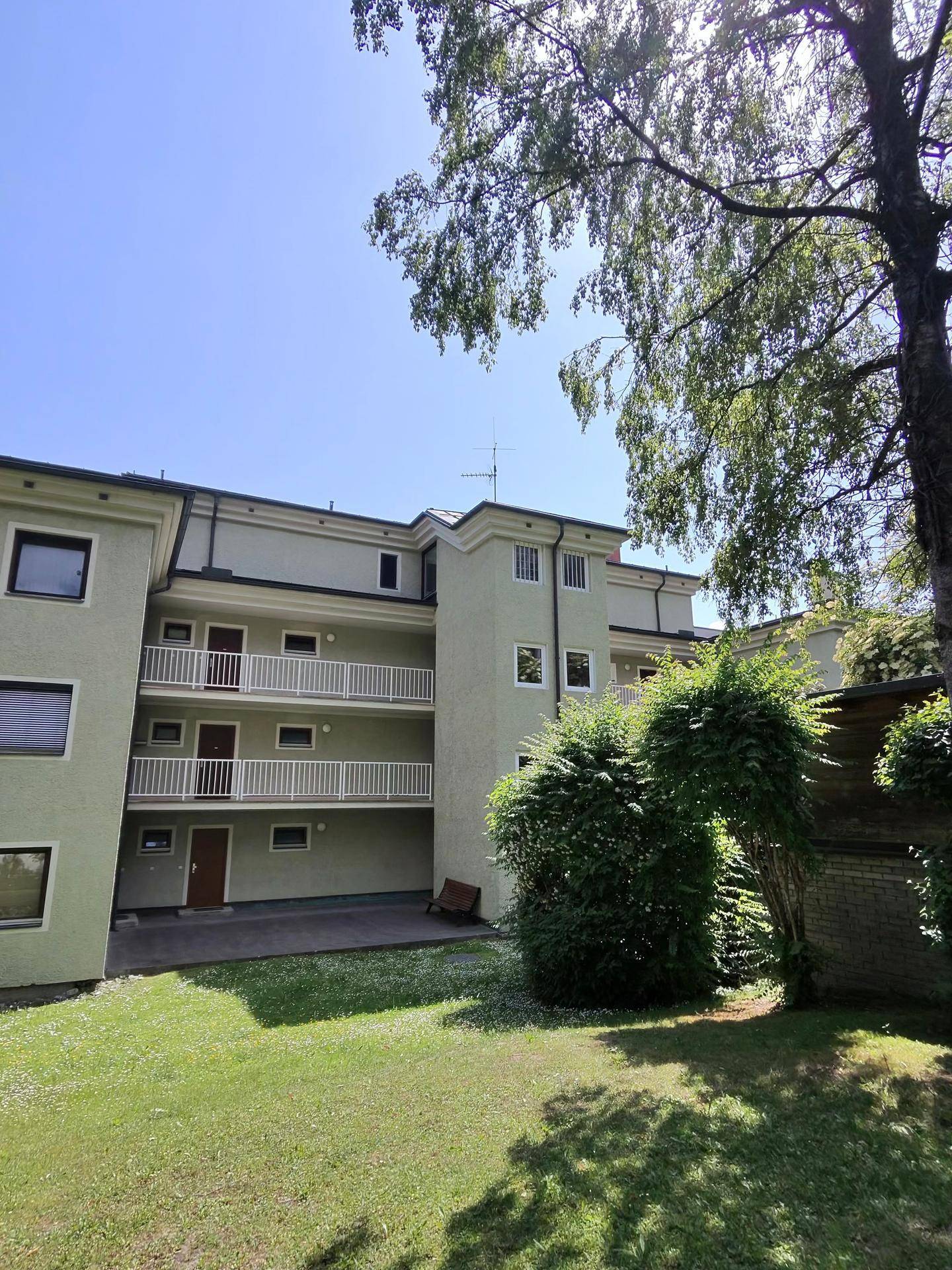 Fassade des Wohngebäudes mit Balkonen und gepflegtem Rasen im Vordergrund.