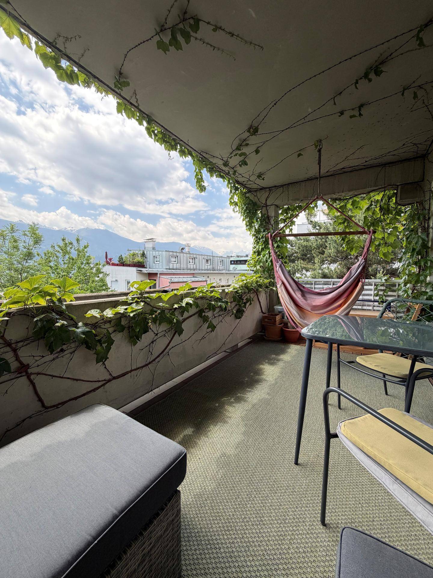 Überdachter Balkon mit Hängematte, Sitzbereich und beeindruckendem Bergblick.