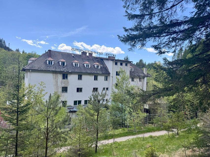 Das Hotelgebäude, umgeben von Bäumen, mit einem traditionellen Dach und Gaubenfenstern.