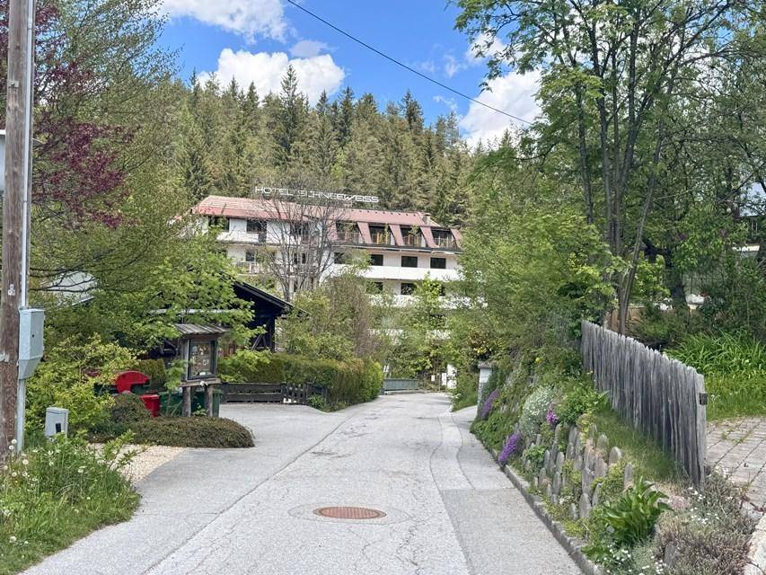 Zufahrtsweg zum Hotel, umgeben von üppiger Vegetation und einem Holzzaun in ländlicher Umgebung.